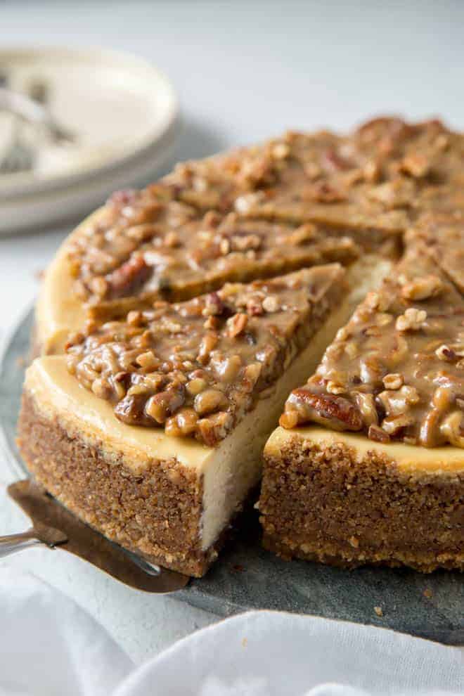 A cake knife removes a piece of pecan pie cheesecake.