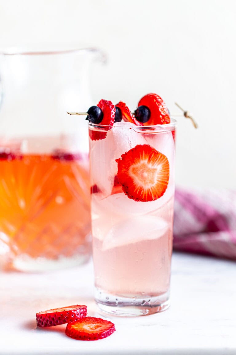 Strawberry sangria in glass with ice and fruit garnish.