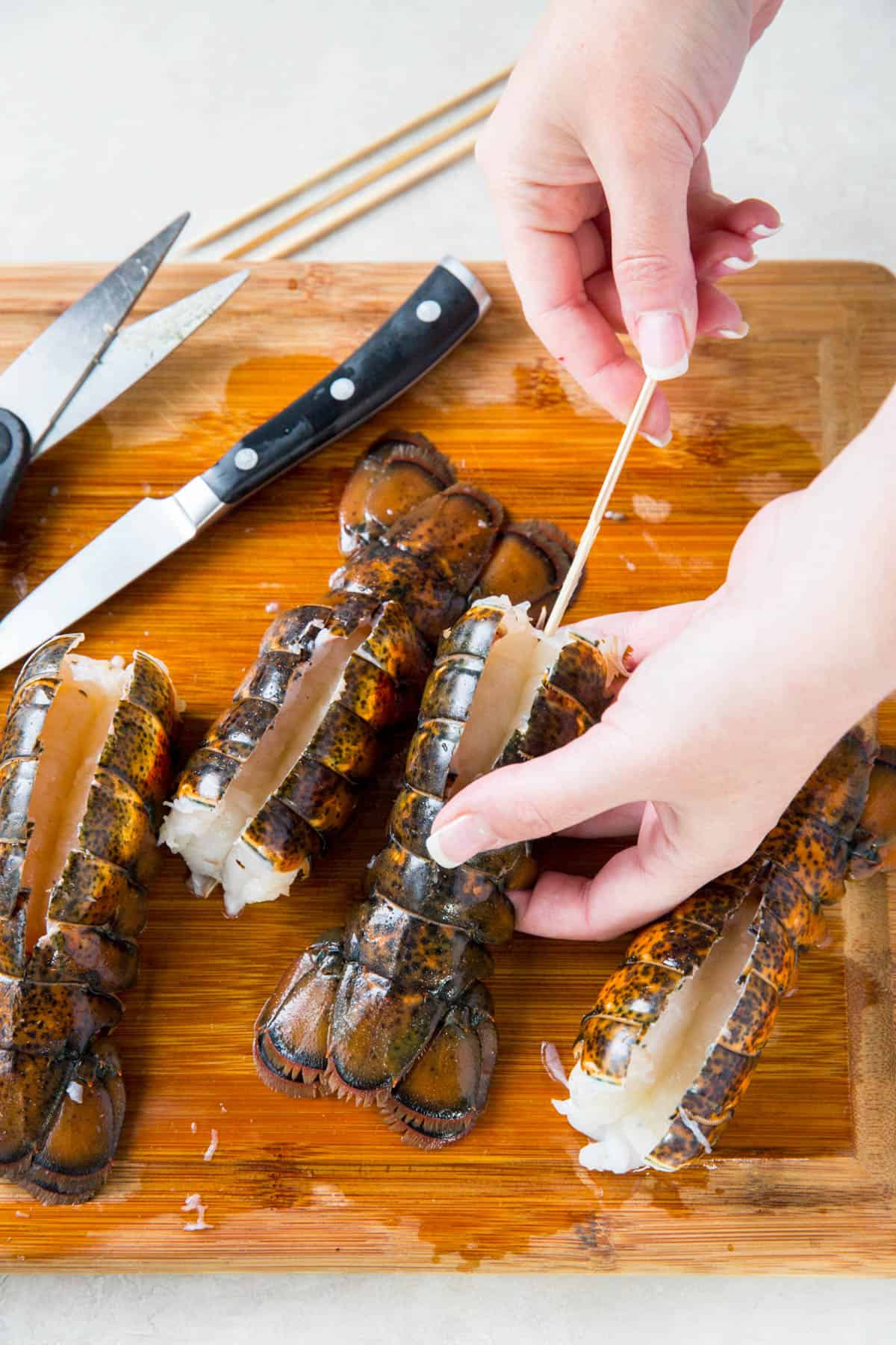 Inserting wooden skewers into lobster tails.