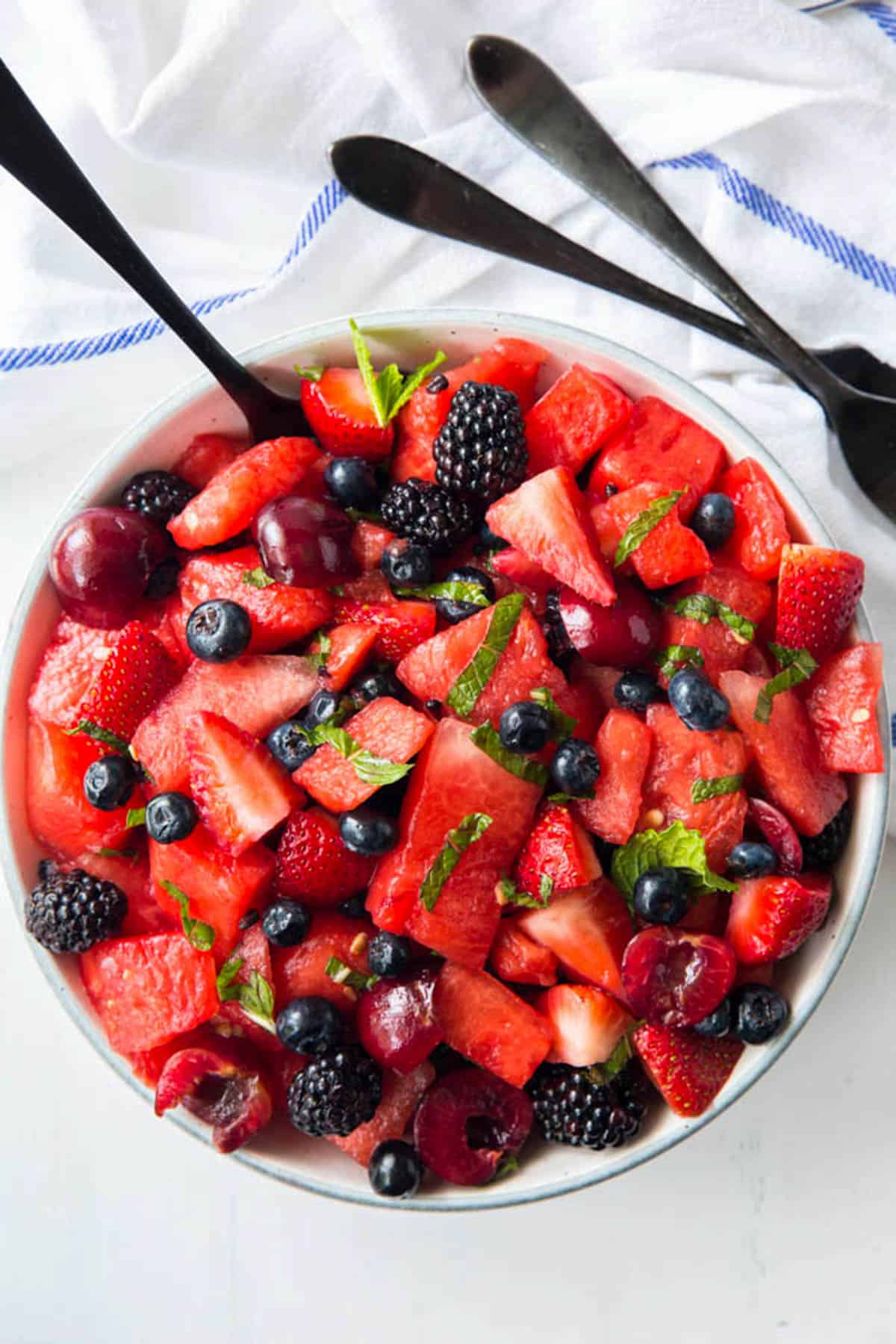 A large bowl of watermelon fruit salad with a serving spoon in it ready for serving.