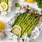 Grilled asparagus in foil with lemon slices and lemon zest.