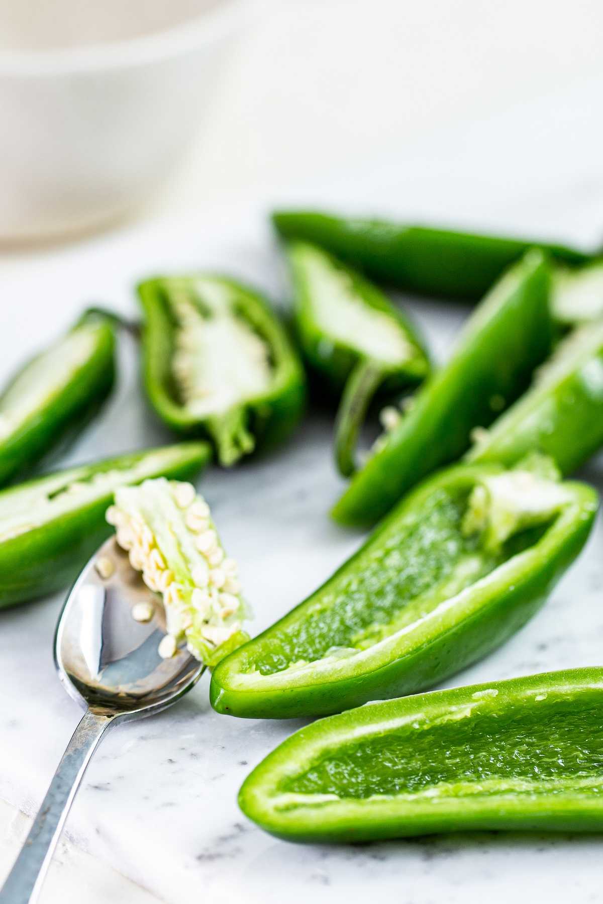 Removing seeds and membranes from jalapeño halves to prepare for stuffed jalapeño poppers