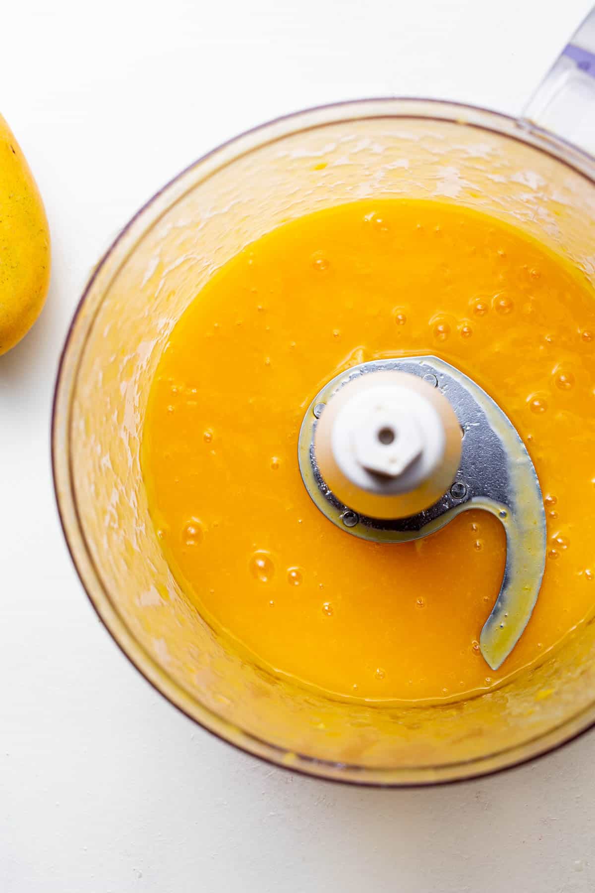 Pureed mango with other ingredients in a food processor.