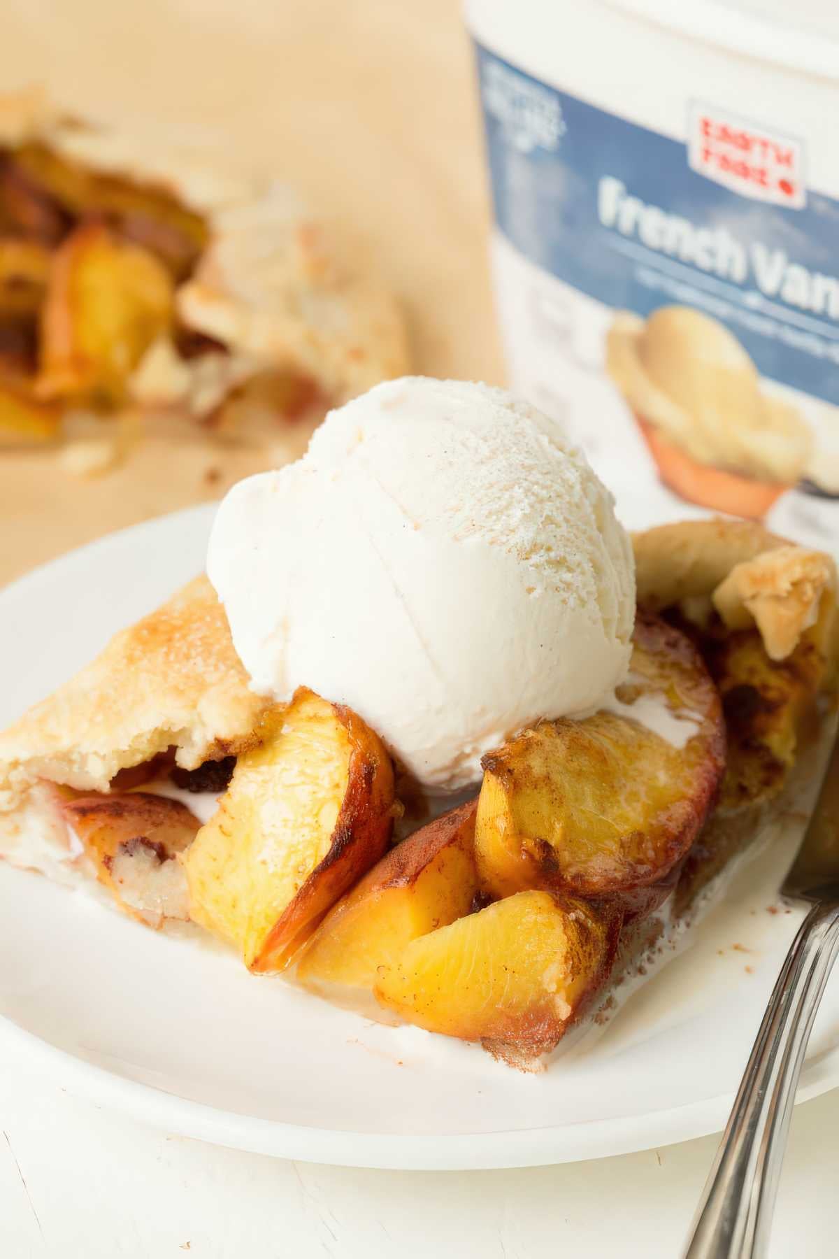 Slice of peach crostata served with a scoop of vanilla ice cream