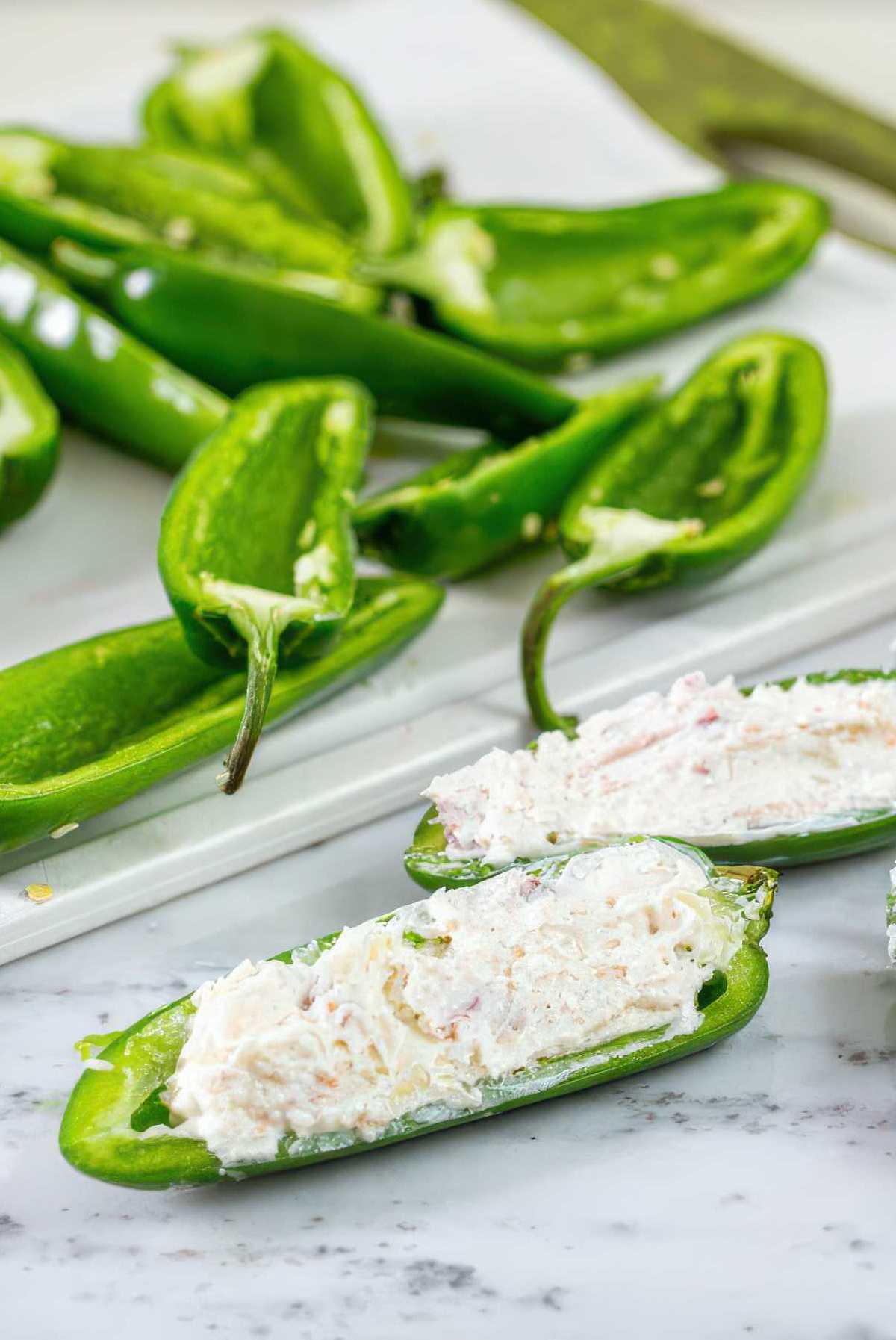 Filling jalapeño halves with creamy cheese mixture for grilled jalapeño poppers