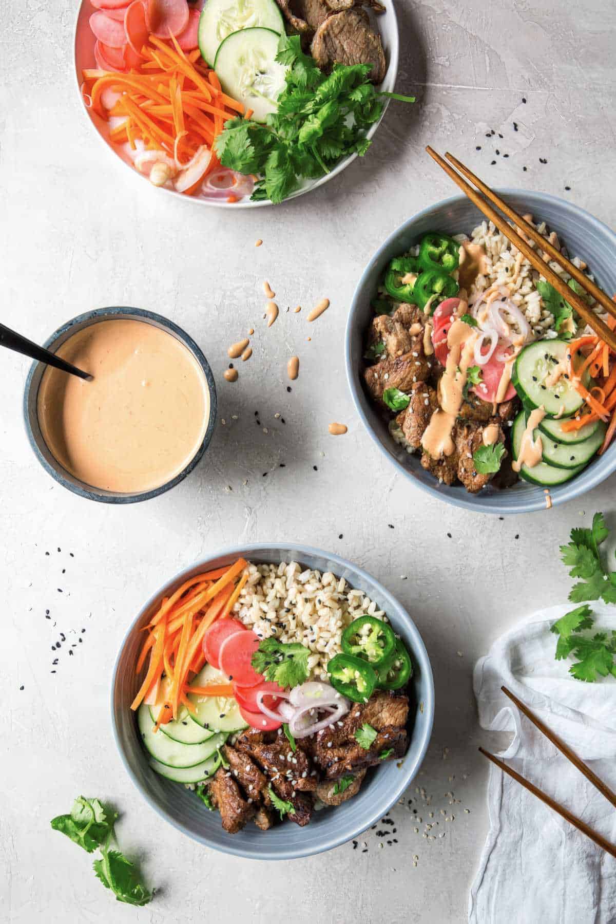 Vietnamese rice bowls with marinated pork, pickled veggies, fresh herbs, and spicy mayo