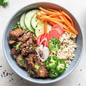 Healthy Banh Mi bowl with brown rice, pork tenderloin, carrots, radishes, cucumber, and jalapeños