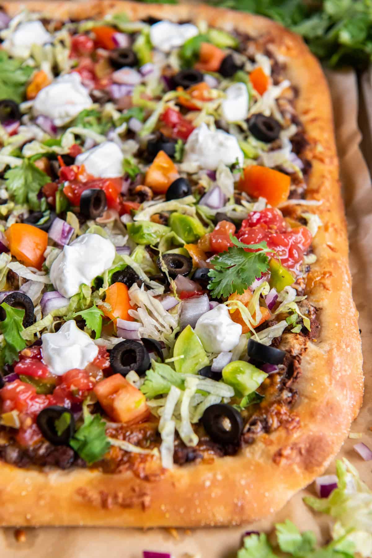 A close up photo of the baked taco pizza with the fresh ingredients layered on top. 