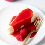 a piece of cheesecake on a plate with raspberry sauce on it