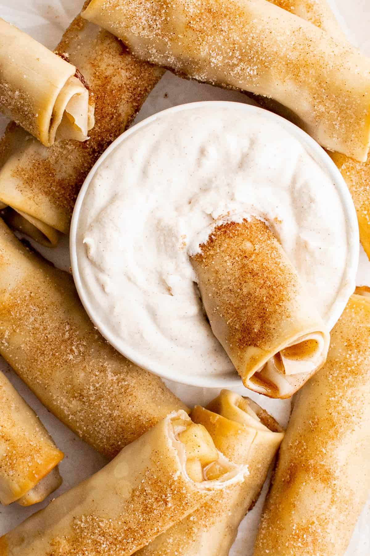 A baked apple pie egg roll dipped into the cinnamon whipped cream.