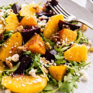 Roasted beet and orange salad on a serving plate with a fork.