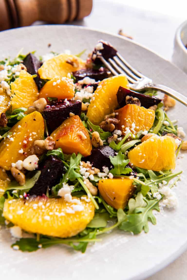 Roasted beet and orange salad on a serving plate with a fork.