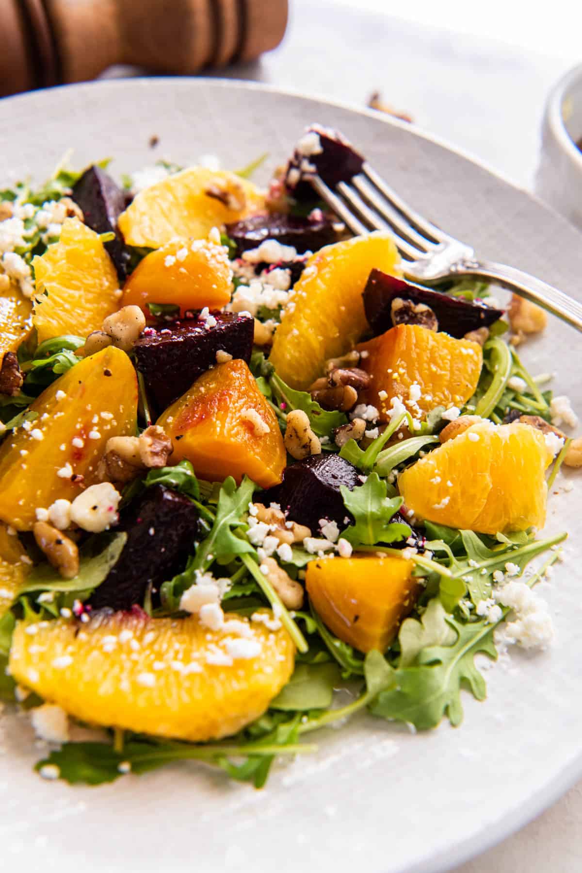 Roasted beet and orange salad on a serving plate with a fork. 