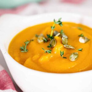 Close-up of smooth autumn squash soup topped with toasted pumpkin seeds and thyme. Title: sauteing-vegetables-for-autumn-squash-soup