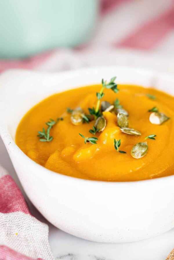 Close-up of smooth autumn squash soup topped with toasted pumpkin seeds and thyme. Title: sauteing-vegetables-for-autumn-squash-soup