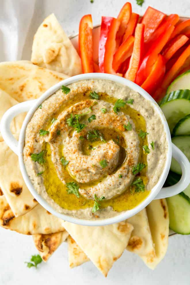 A bowl of baba ganoush with olive oil and parsley.