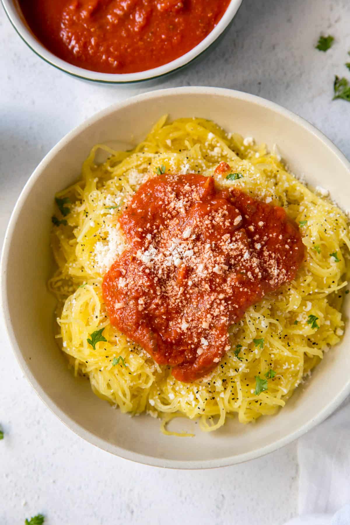 a bowl filled with spaghetti squash and topped with tomato sauce
