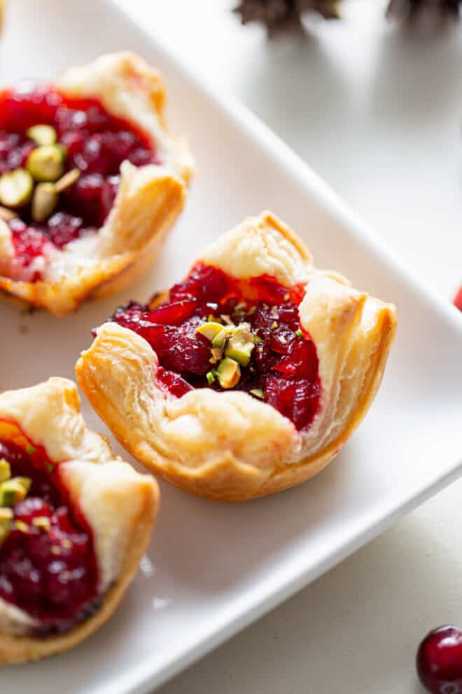 a baked cranberry and brie puff pastry sitting on a white plate