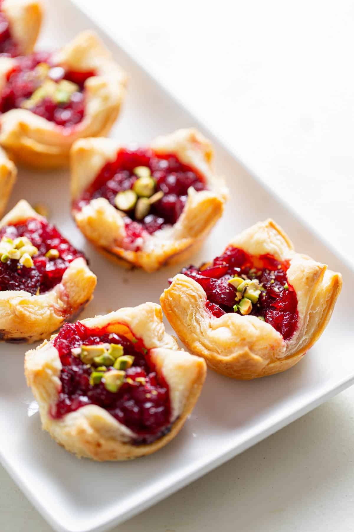 eight cranberry brie bites on a white plate for serving