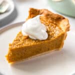 one slice of sweet potato pie on a plate with a scoop of whipped cream on top
