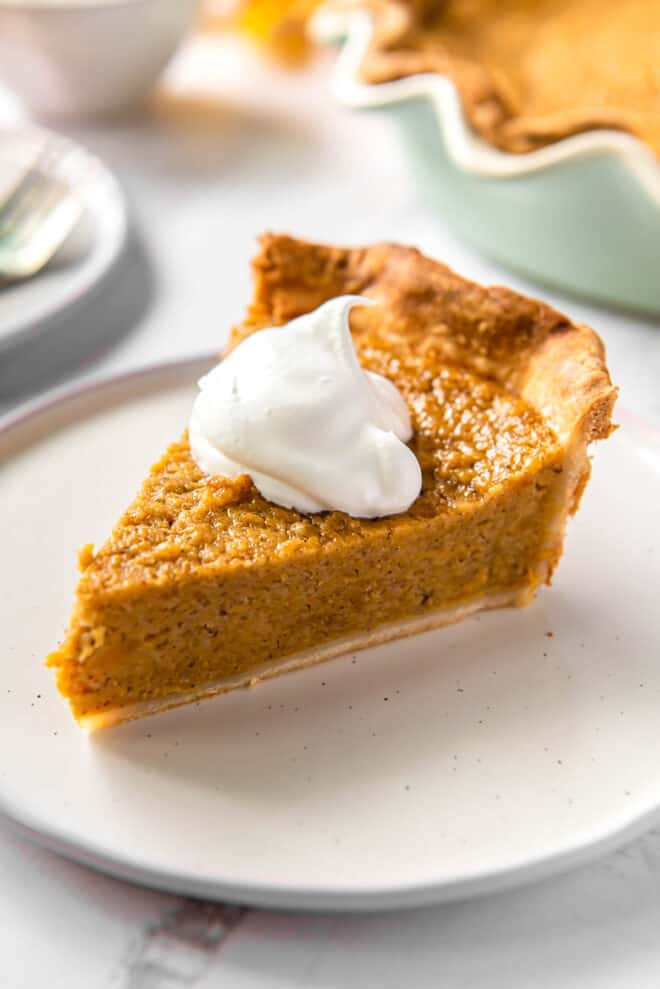 one slice of sweet potato pie on a plate with a scoop of whipped cream on top