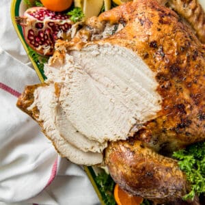 a roasted thanksgiving turkey on a pan with fresh citrus