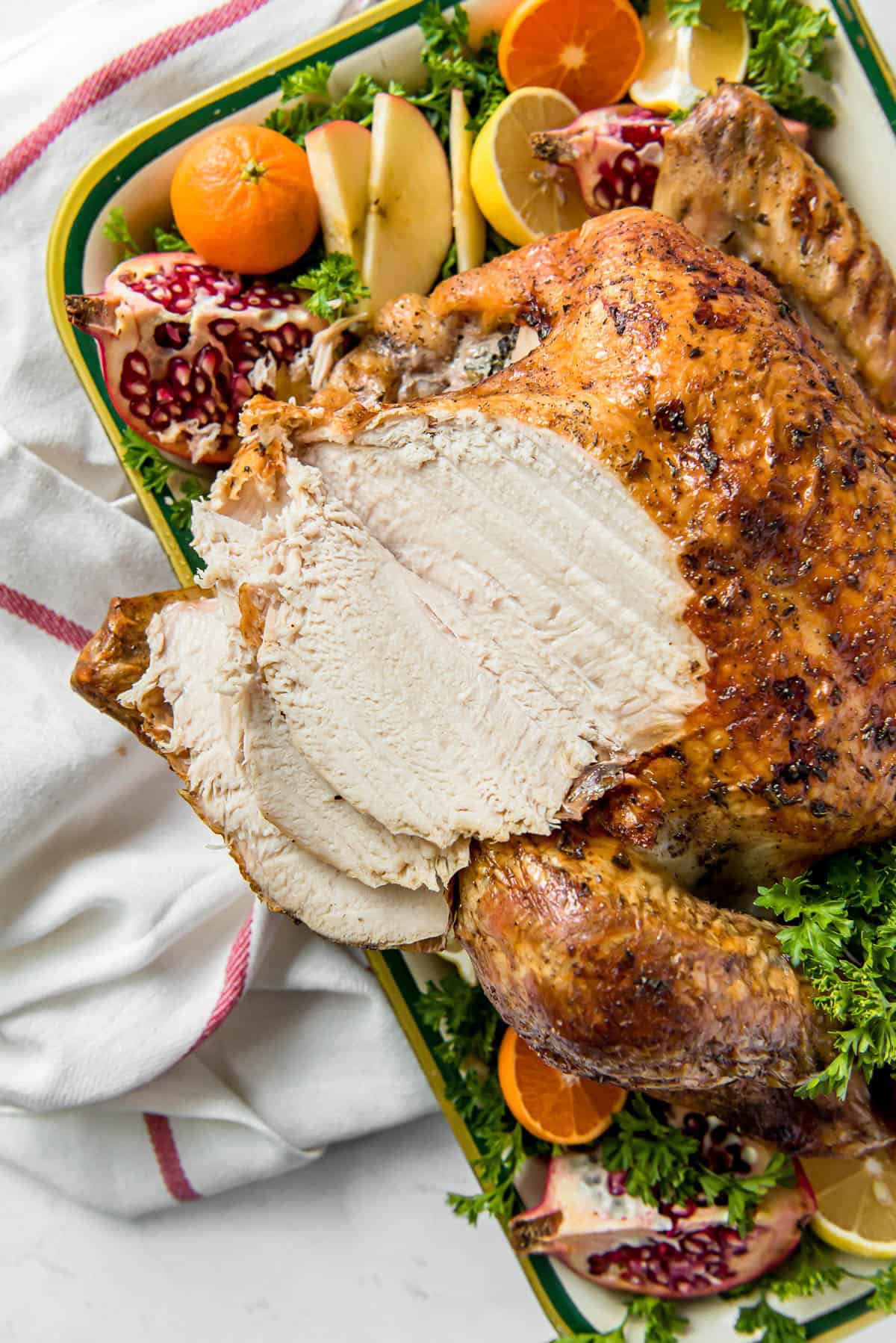 a roasted thanksgiving turkey on a pan with fresh citrus