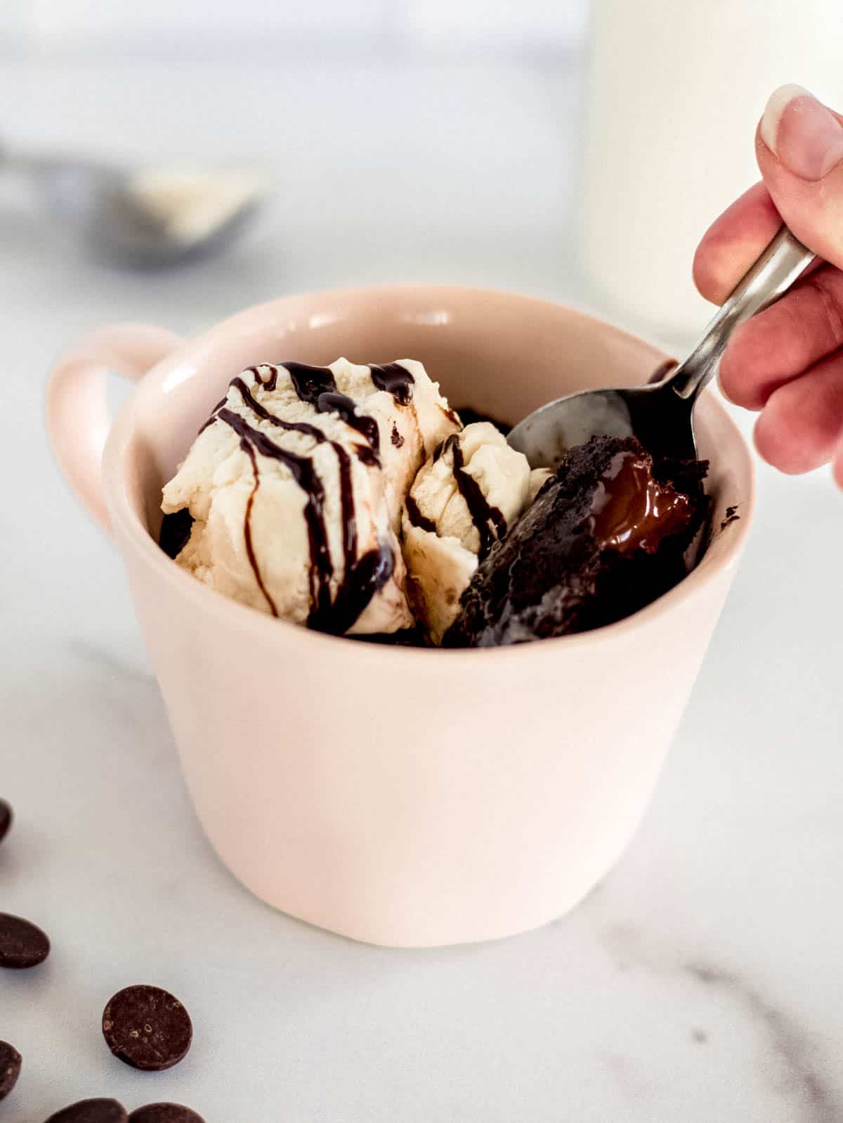 a scoop taking a scoop of brownie in a mug 