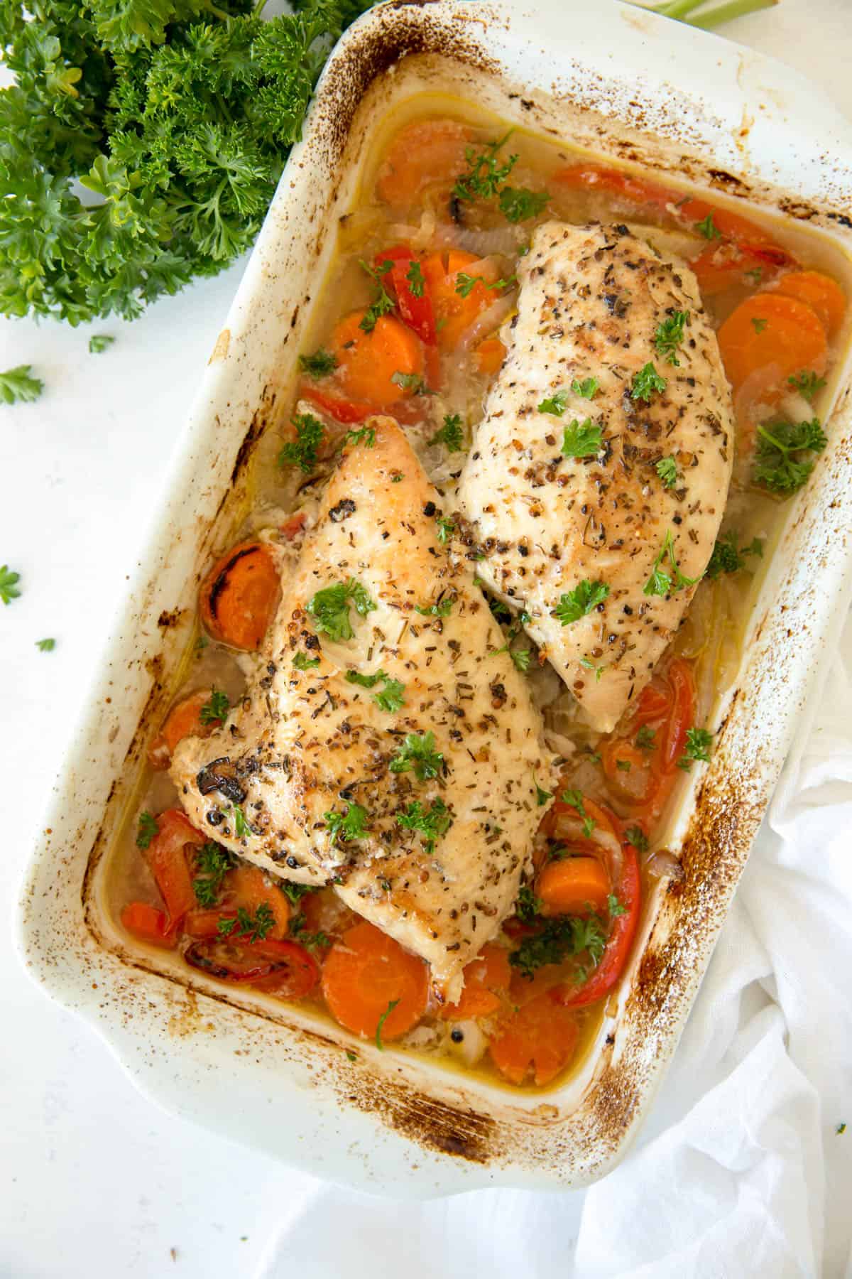A turkey tenderloin baked in a casserole dish with carrots, peppers and onions.