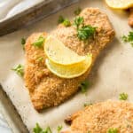 A few baked chicken cutlets on a baking sheet after baking in the oven.