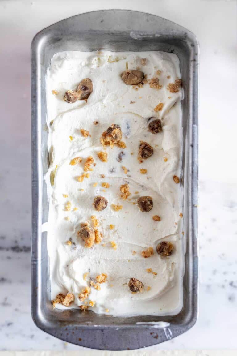 Chocolate chip cookie dough ice cream frozen in a loaf pan with cookie dough pieces on top.