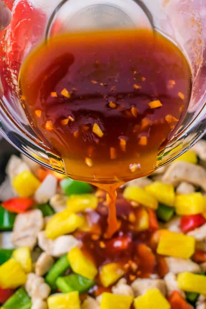 sweet and sour sauce pouring over chicken and bell peppers