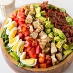 a large wooden bowl with lettuce, boiled egg, tomatoes, grilled turkey, avocado and turkey bacon