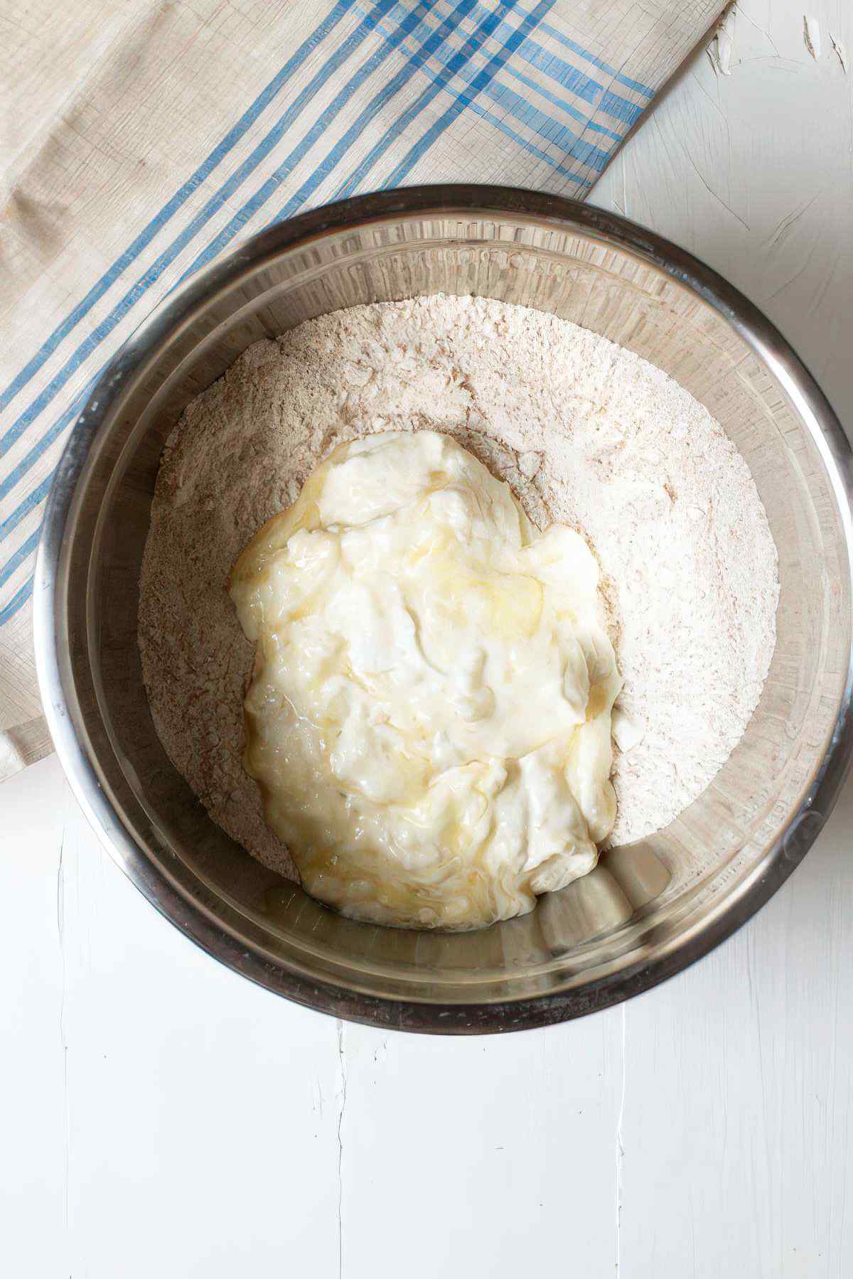 Adding wet ingredients to dry ingredients to make blackberry muffin batter