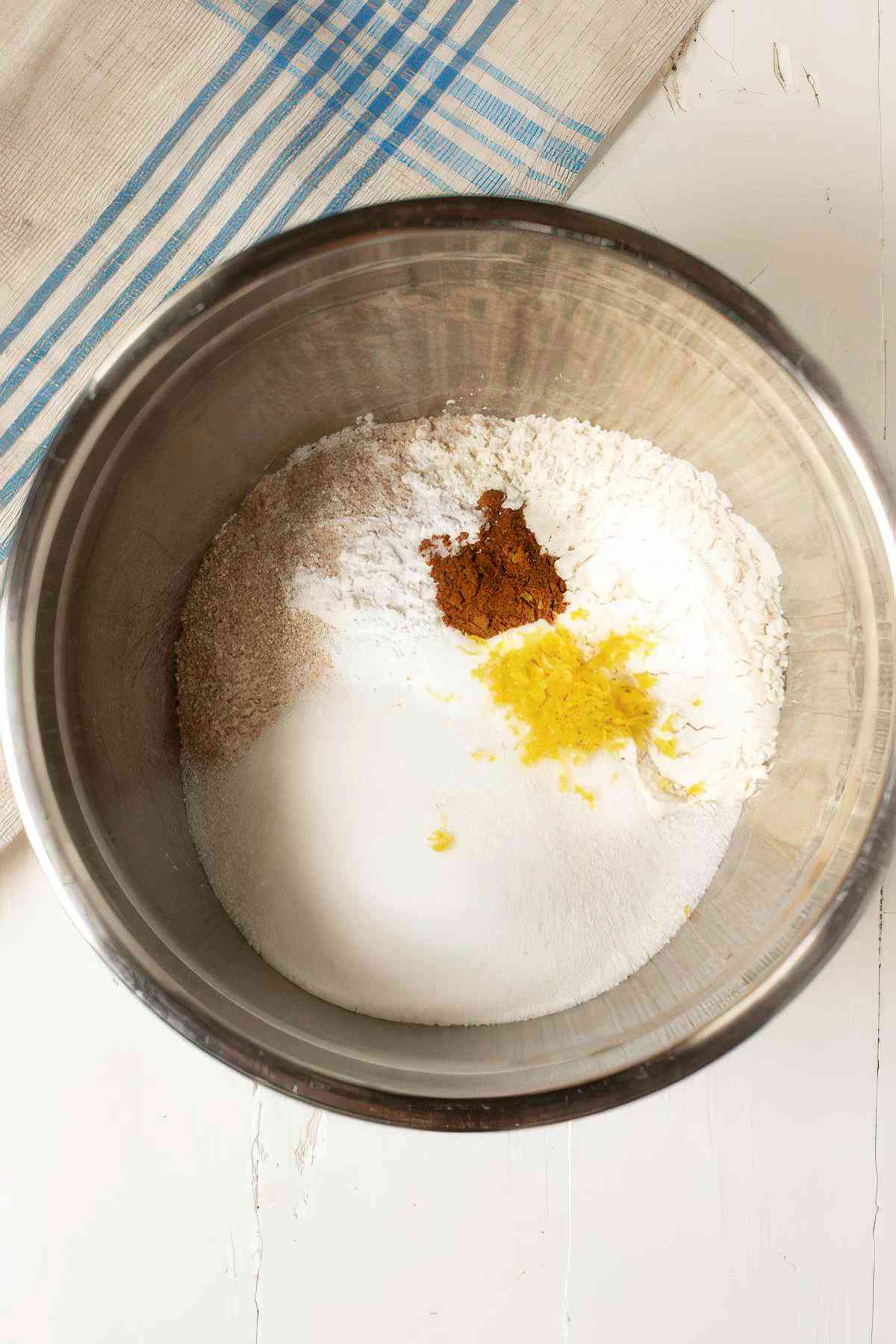Dry ingredients including flour, sugar, cinnamon, and lemon zest in a bowl for blackberry muffins