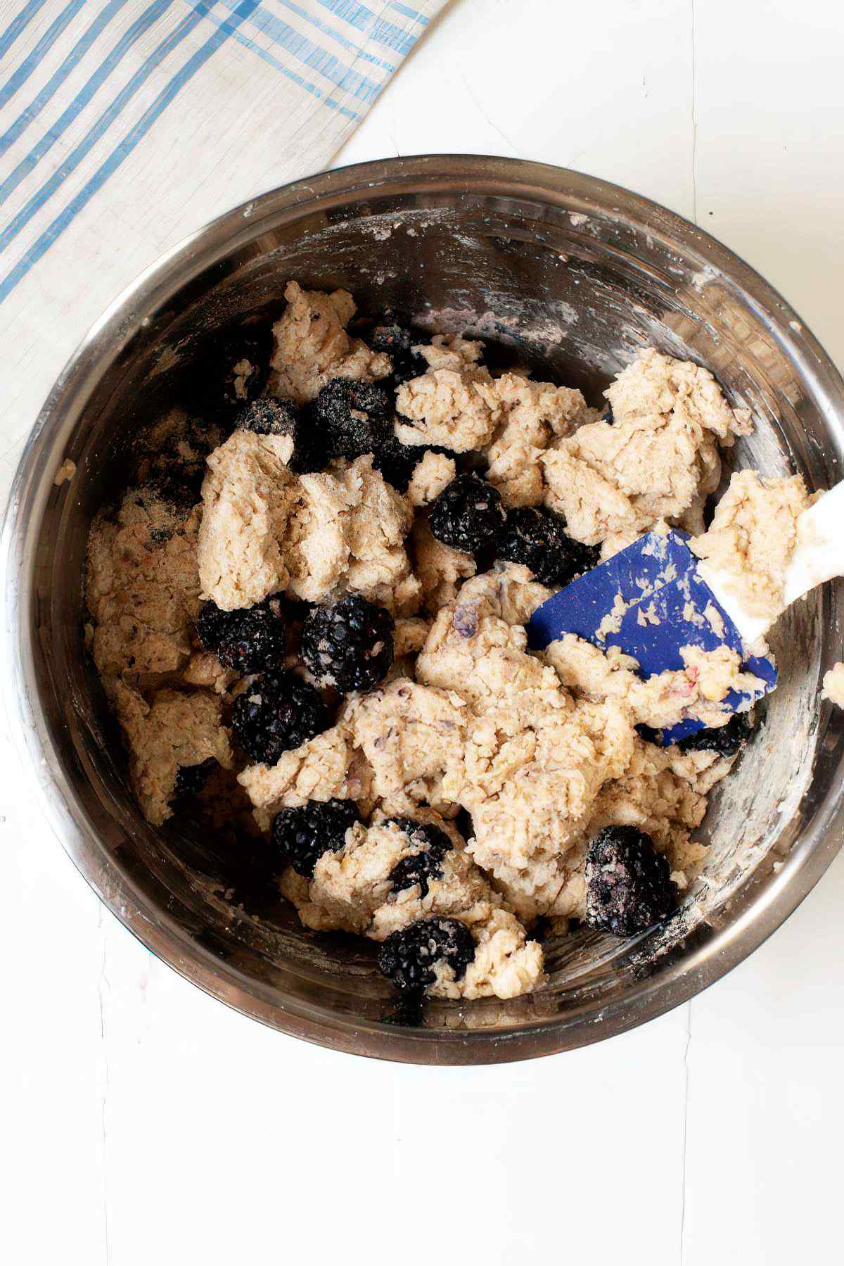 Folding fresh blackberries into thick muffin batter for blackberry muffins