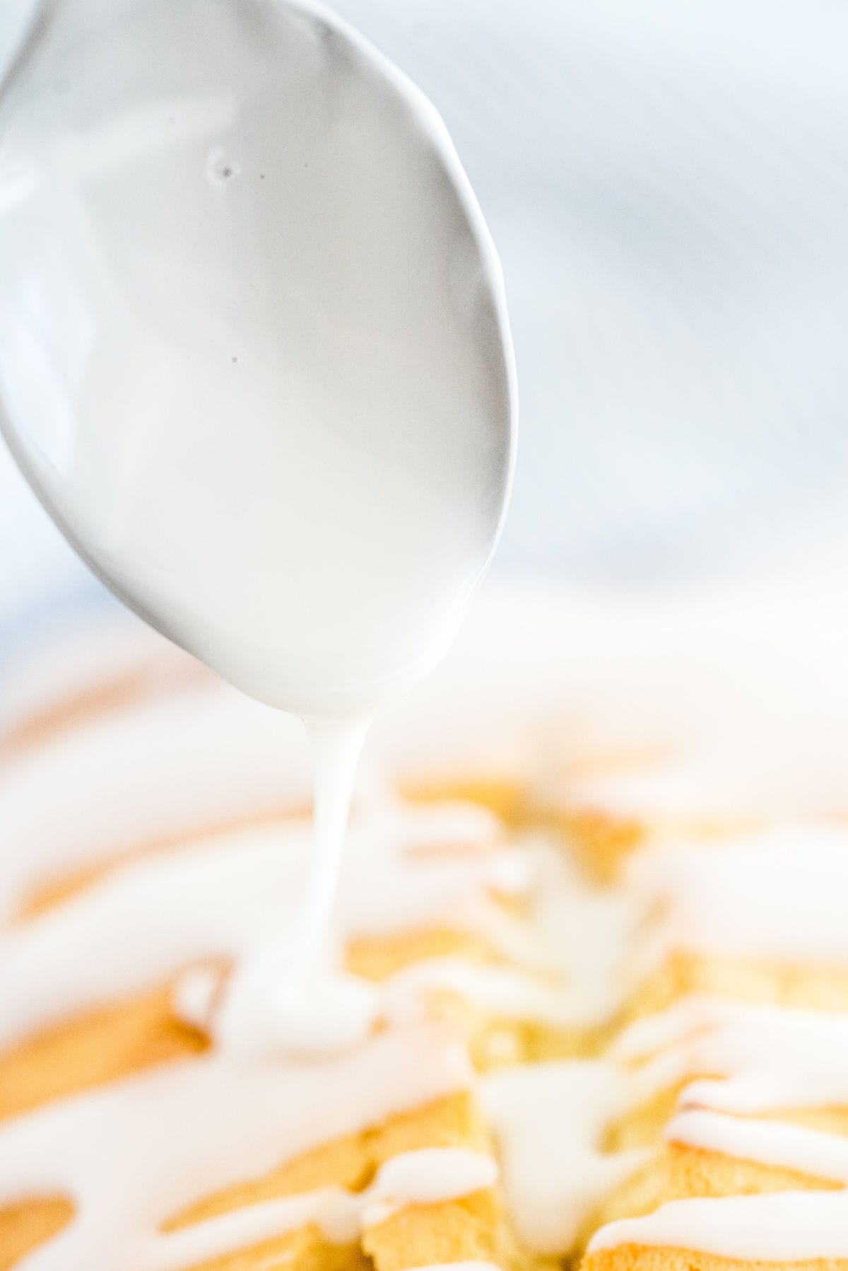 Lemon glaze being drizzled over a homemade lemon loaf cake.