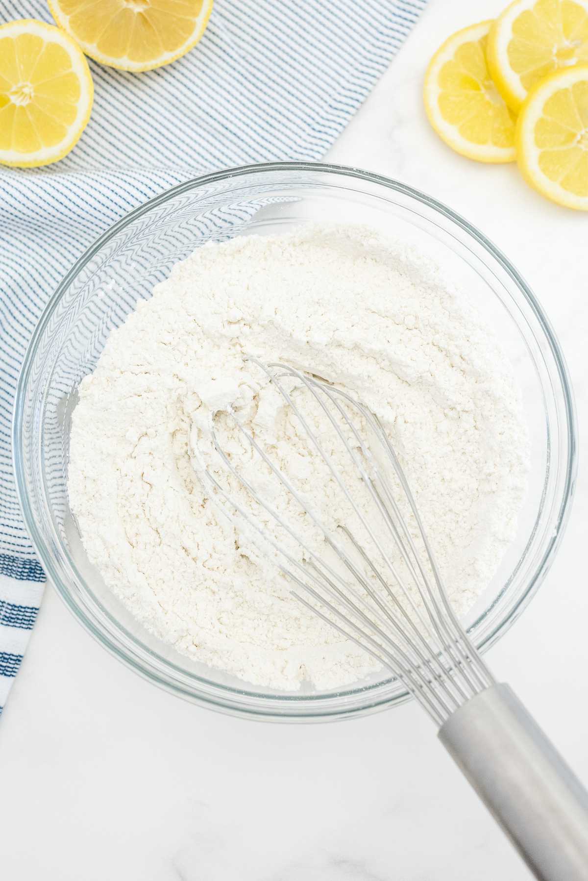 Whisking flour and dry ingredients in a bowl to make lemon loaf cake batter.
