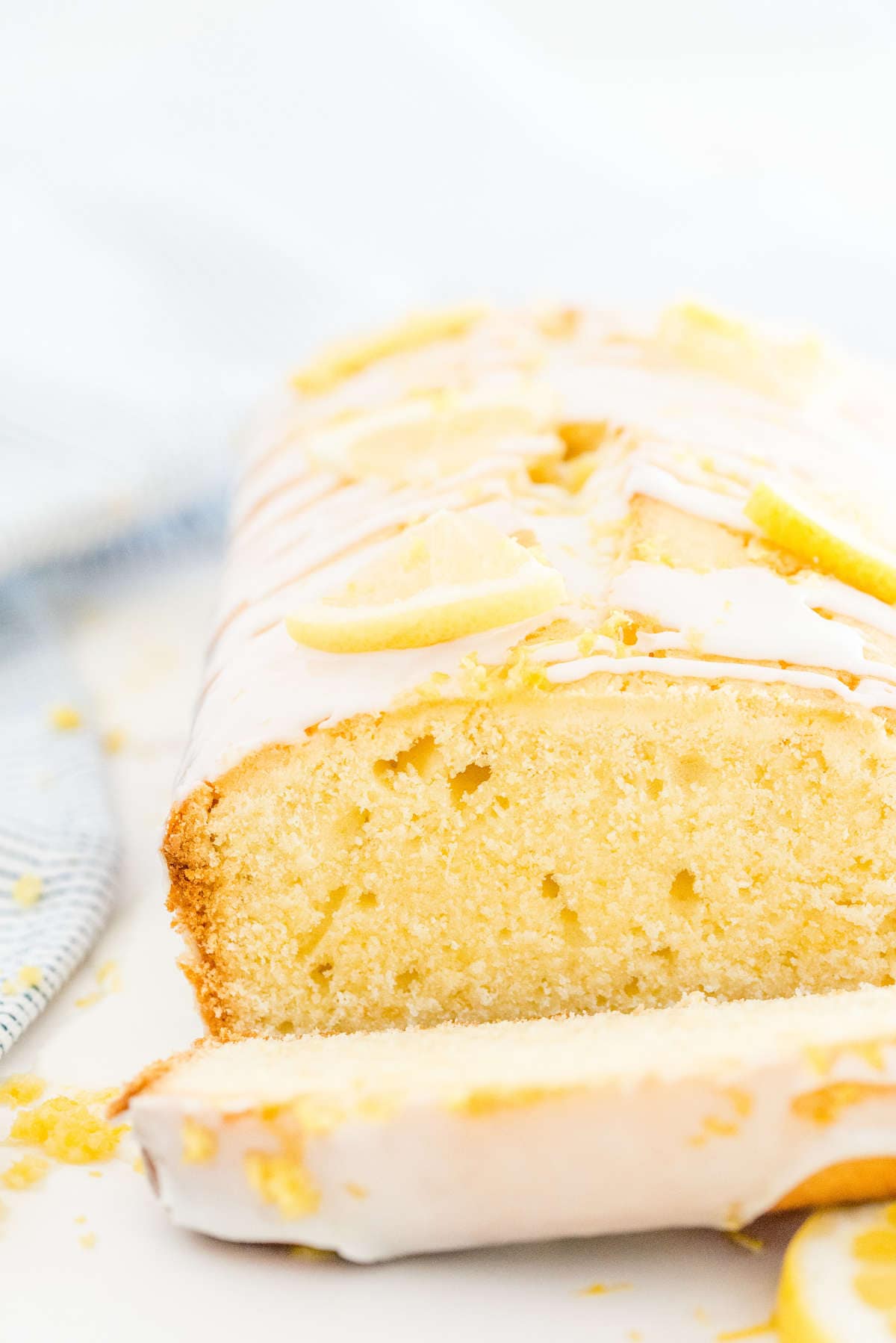 Close-up of a moist lemon loaf cake slice showing the soft crumb and lemon glaze on top.