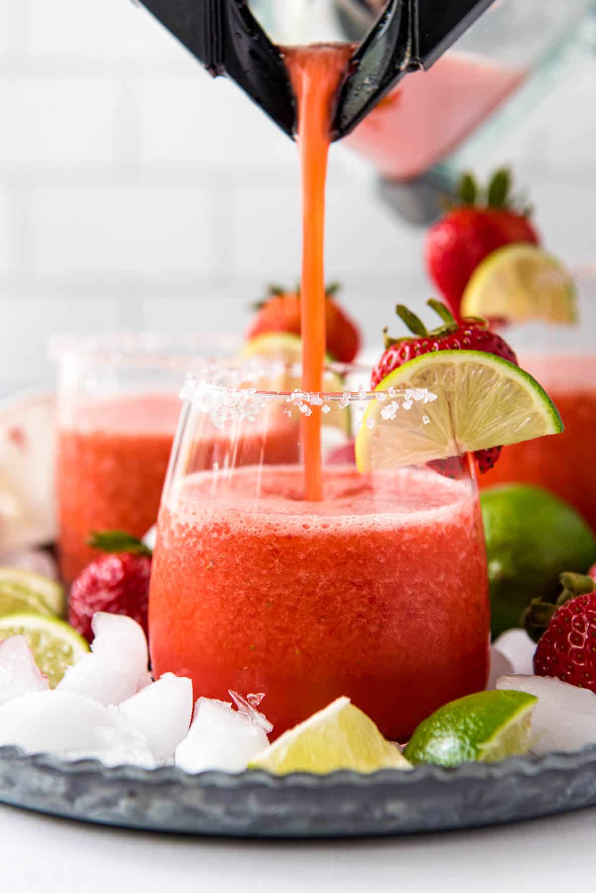 Pouring a frozen strawberry margarita into a glass for serving.