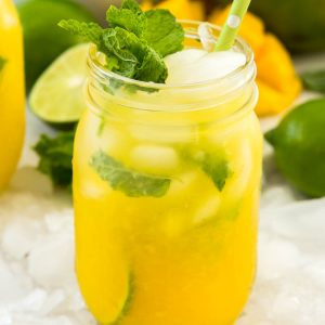 A mason jar filled with mango mojito and garnished with fresh mint leaves