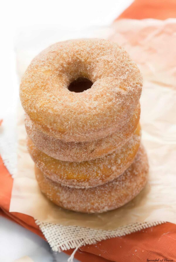 Stack of baked pumpkin donuts covered in cinnamon sugar.