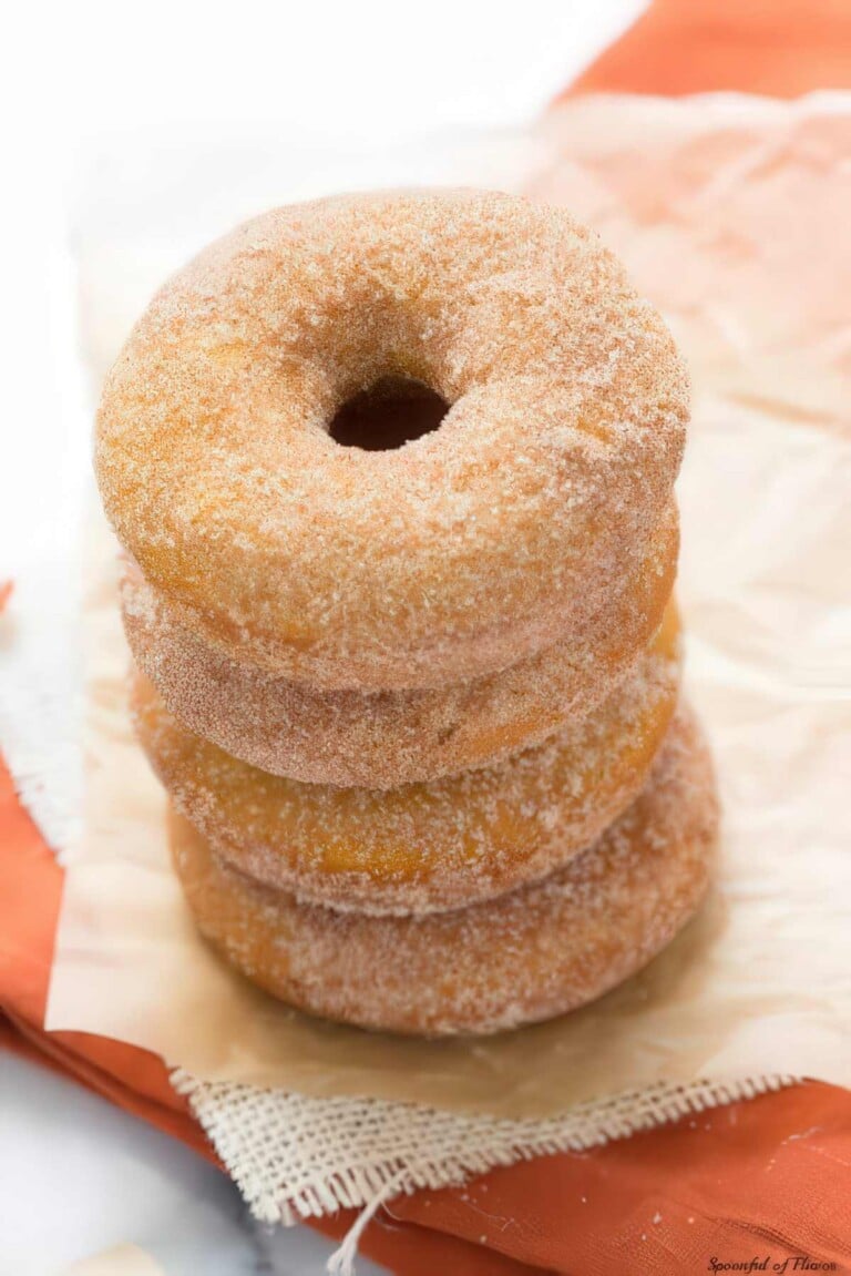 Stack of baked pumpkin donuts covered in cinnamon sugar.
