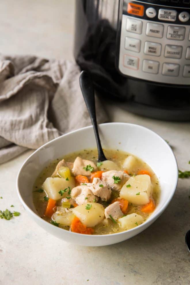 a bowl of chicken stew sitting next to an Instant Pot on a table