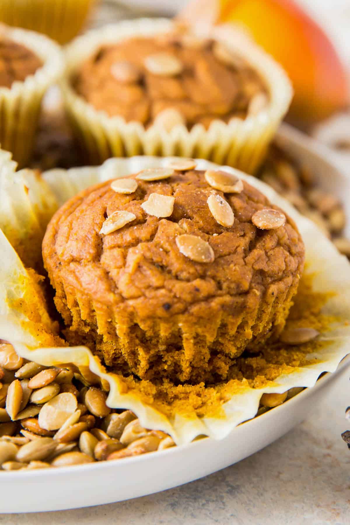 one pumpkin muffin sitting on a plate with pumpkin seeds on top