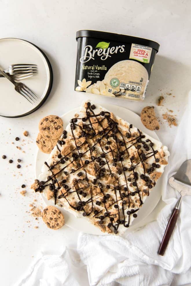 a chocolate chip cookie ice cream cake on a large plate with a carton of Breyers ice cream