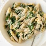 spinach and ricotta pasta in a white bowl with a fork