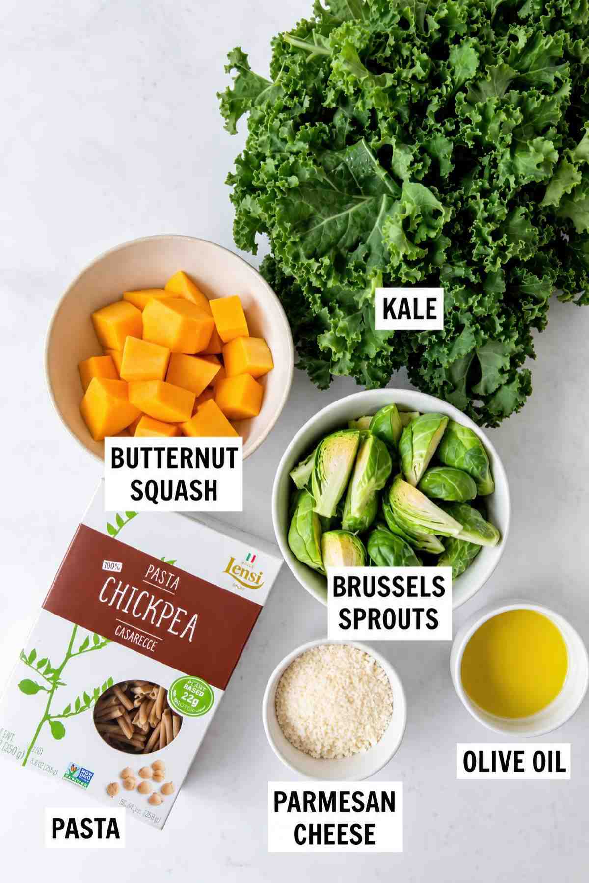 Labeled ingredients: kale, butternut squash, Brussels sprouts, chickpea pasta, Parmesan cheese, and olive oil.