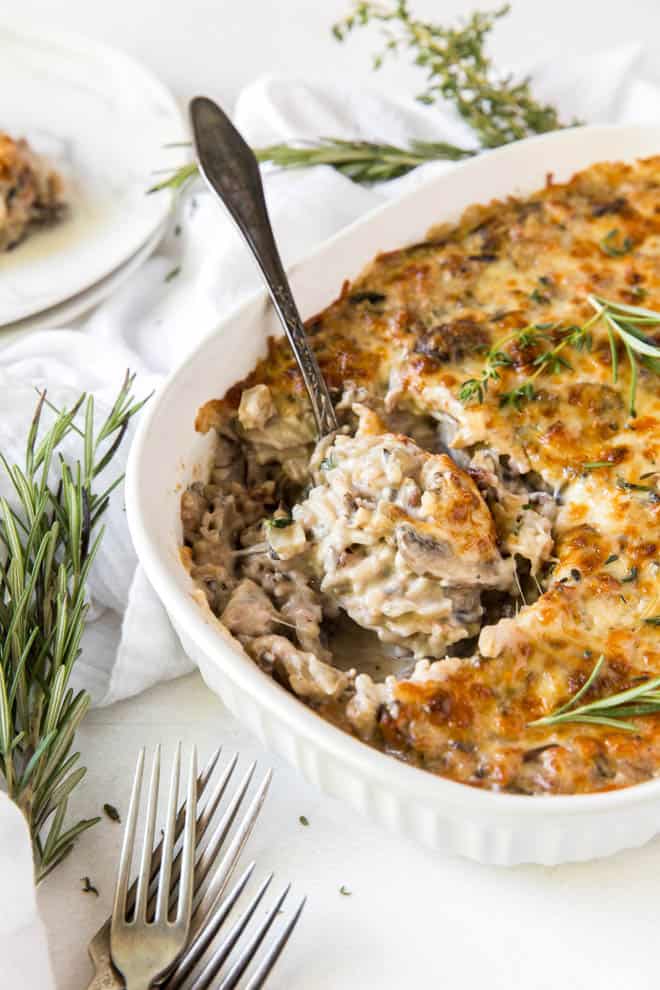 a spoon sitting in a dish of cooked mushroom and wild rice casserole