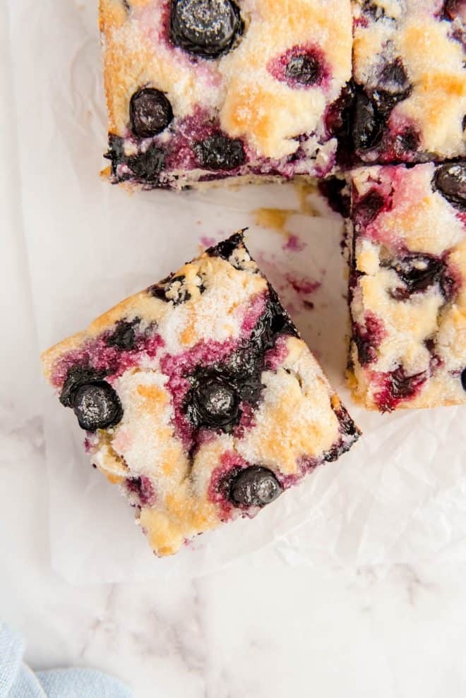 a slice of blueberry breakfast cake on white parchment paper